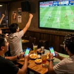 Bóng đá Bet168 fans cheering at a sports bar, engaging in live betting during the match
